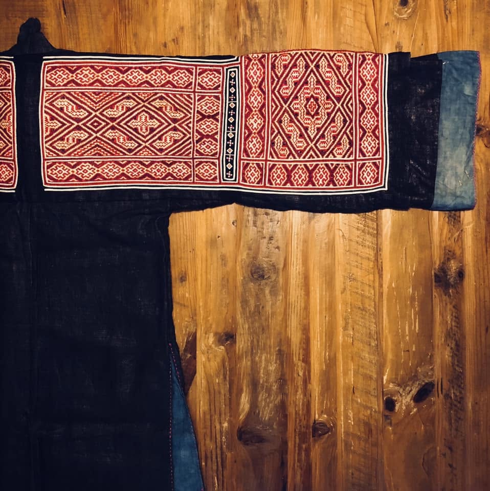 赤と白の幾何学模様の刺繍が施された濃紺の衣服